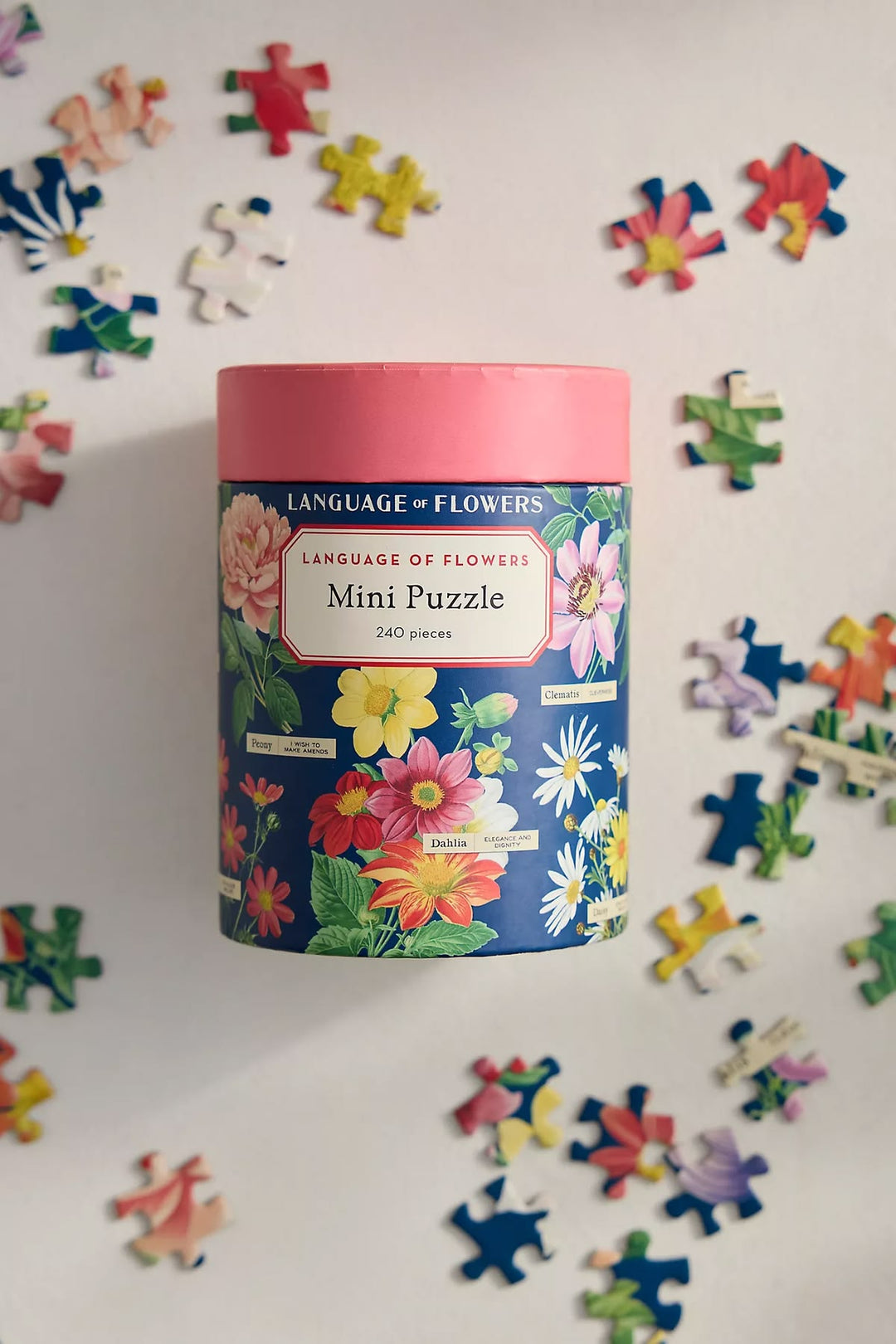 Mini puzzle in a colorful box with scattered puzzle pieces on a light background