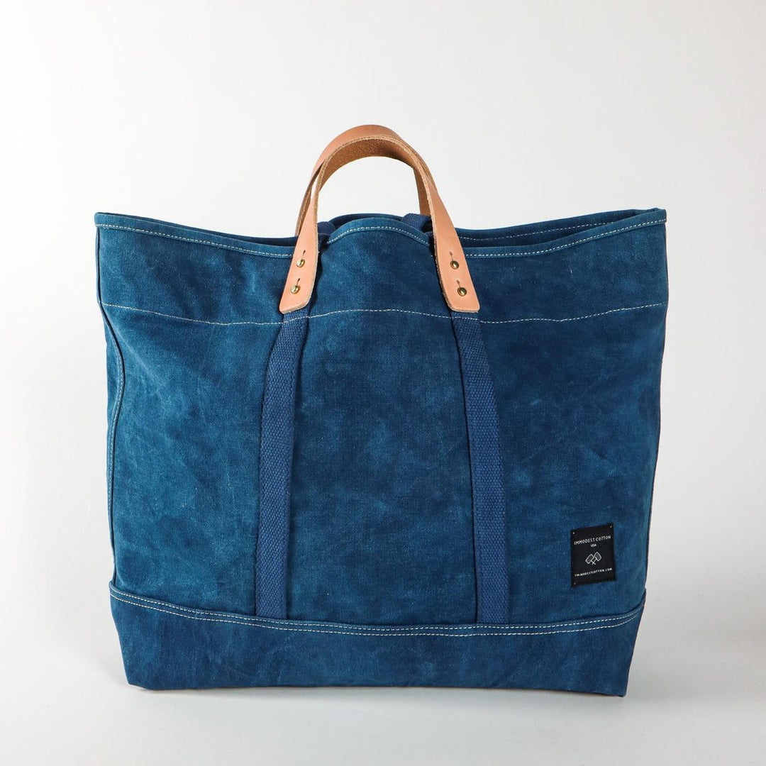 Blue tote bag with leather handle on a white background