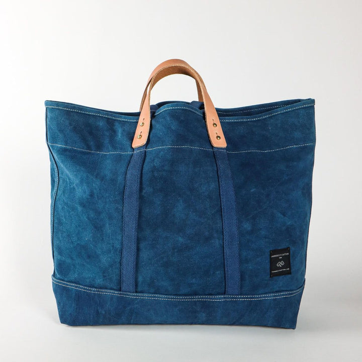 Blue tote bag with leather handle on a white background