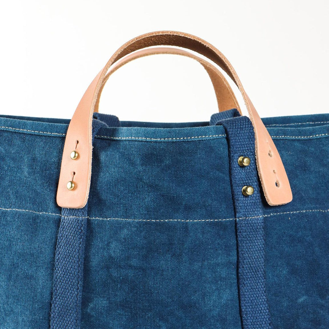 Blue tote bag with leather handles on a white background