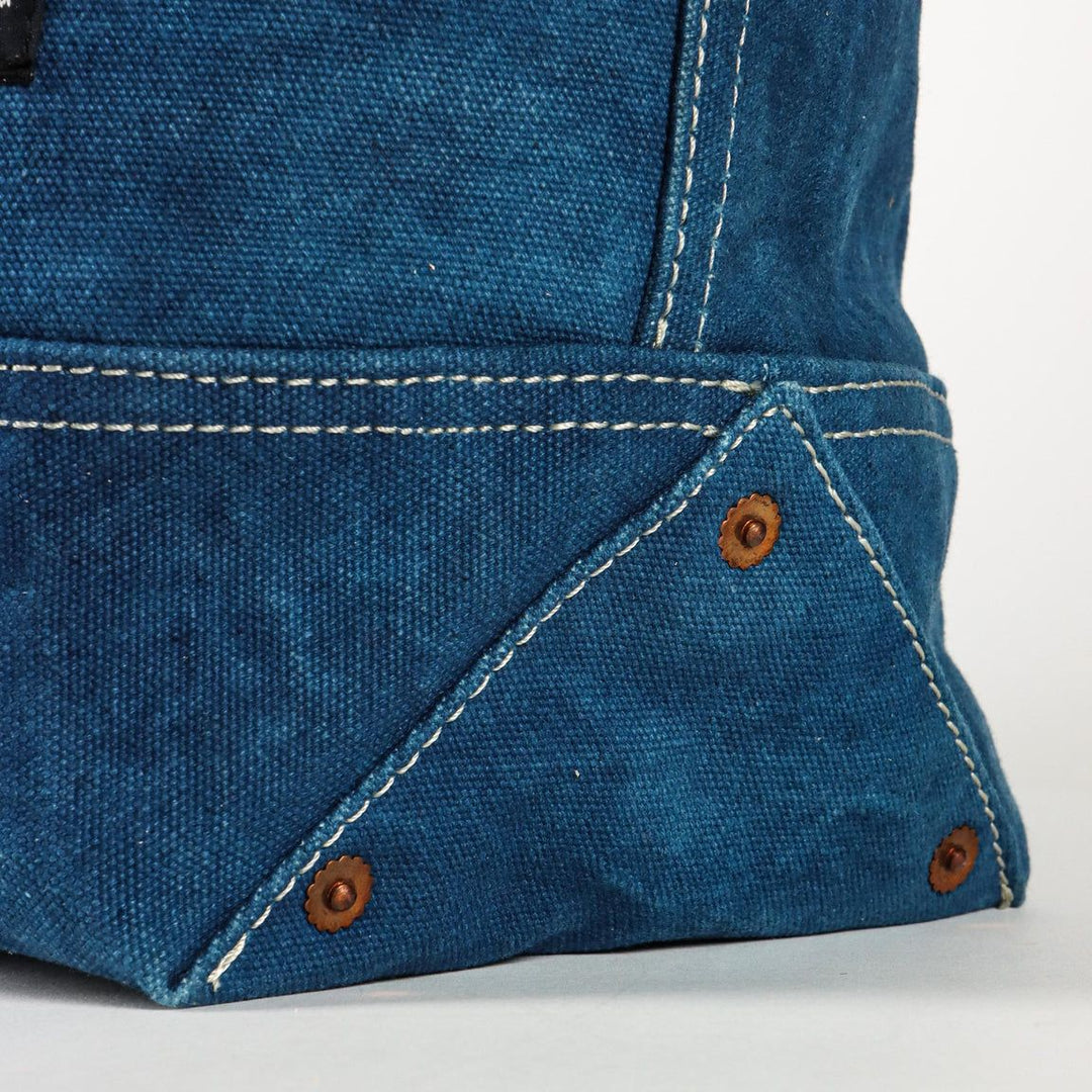 Close-up of a blue denim fabric with stitching and buttons on a white background