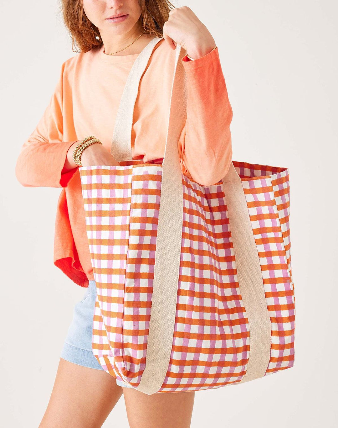Person holding a large checkered bag with a plain background