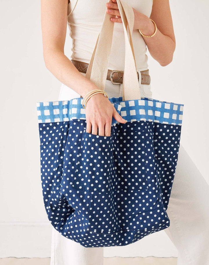 Person holding a blue polka dot tote bag with a white background