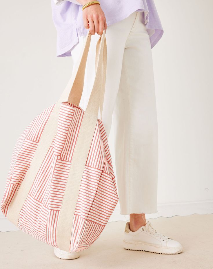 Person holding a striped tote bag with a plain background