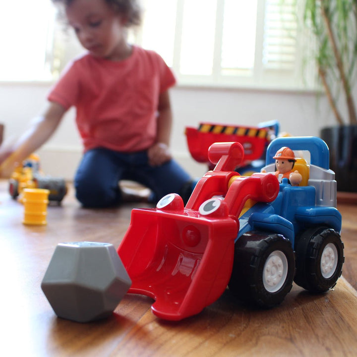 Child playing with toy construction vehicle on a wooden floor