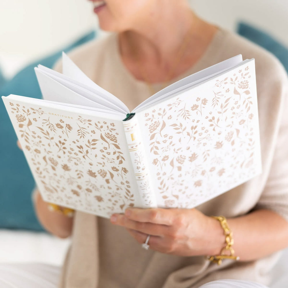 Person holding a book with floral lace design on the cover