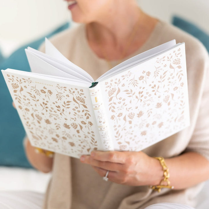 Person holding a book with floral lace design on the cover