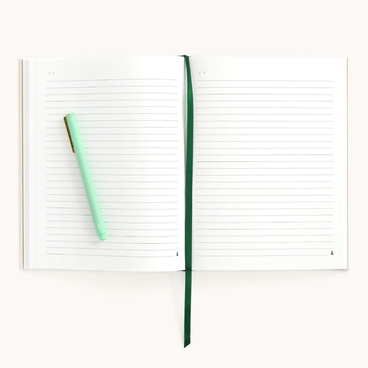 Open notebook with a green pen on a white background