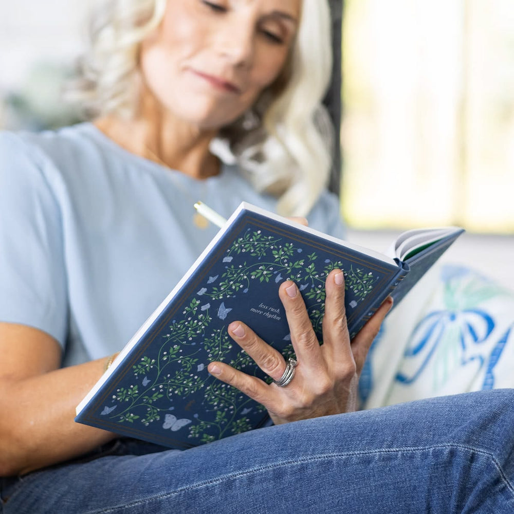 Woman reading a blue book with floral design on a blurred background