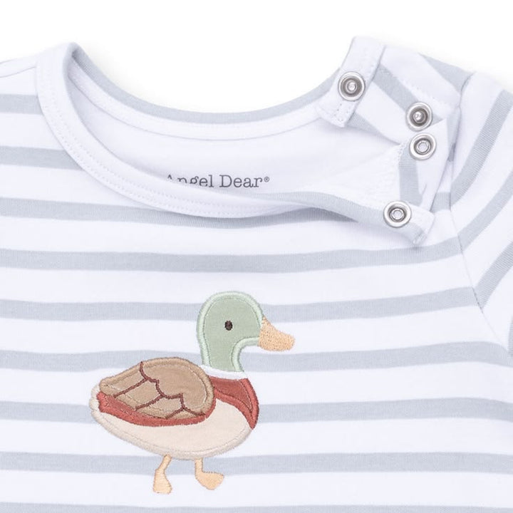 Close-up of a baby long-sleeve top with light gray and white horizontal stripes, featuring a colorful embroidered duck on the chest and three silver snap closures at the collar. The brand name 'Angel Dean' is visible inside the collar.
