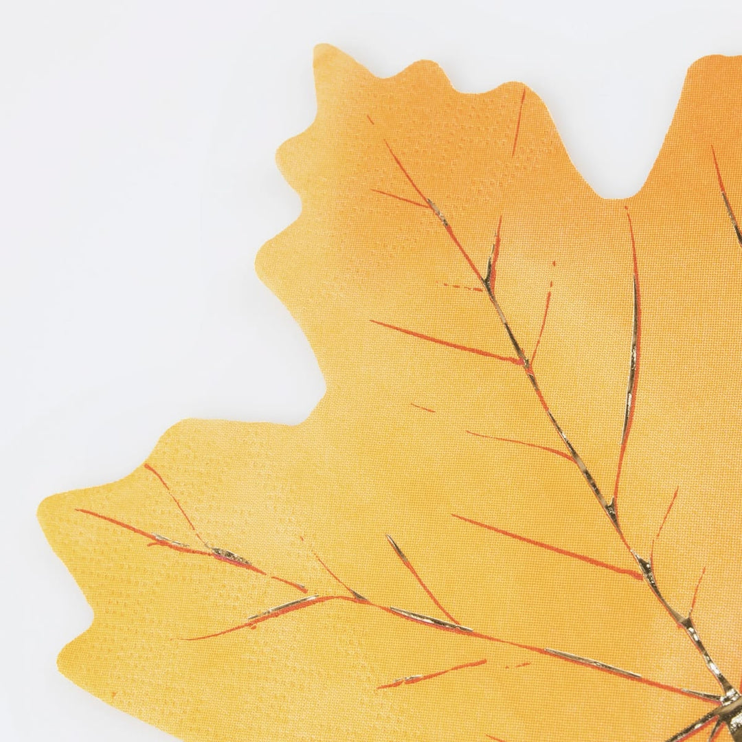 A close-up of a yellow-orange leaf-shaped decorative item with metallic silver branch details on a plain white background.