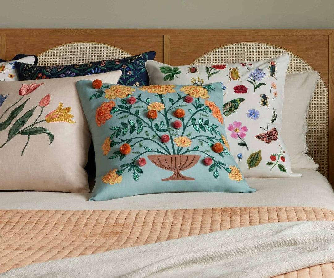 Decorative pillows with floral and botanical patterns on a bed.