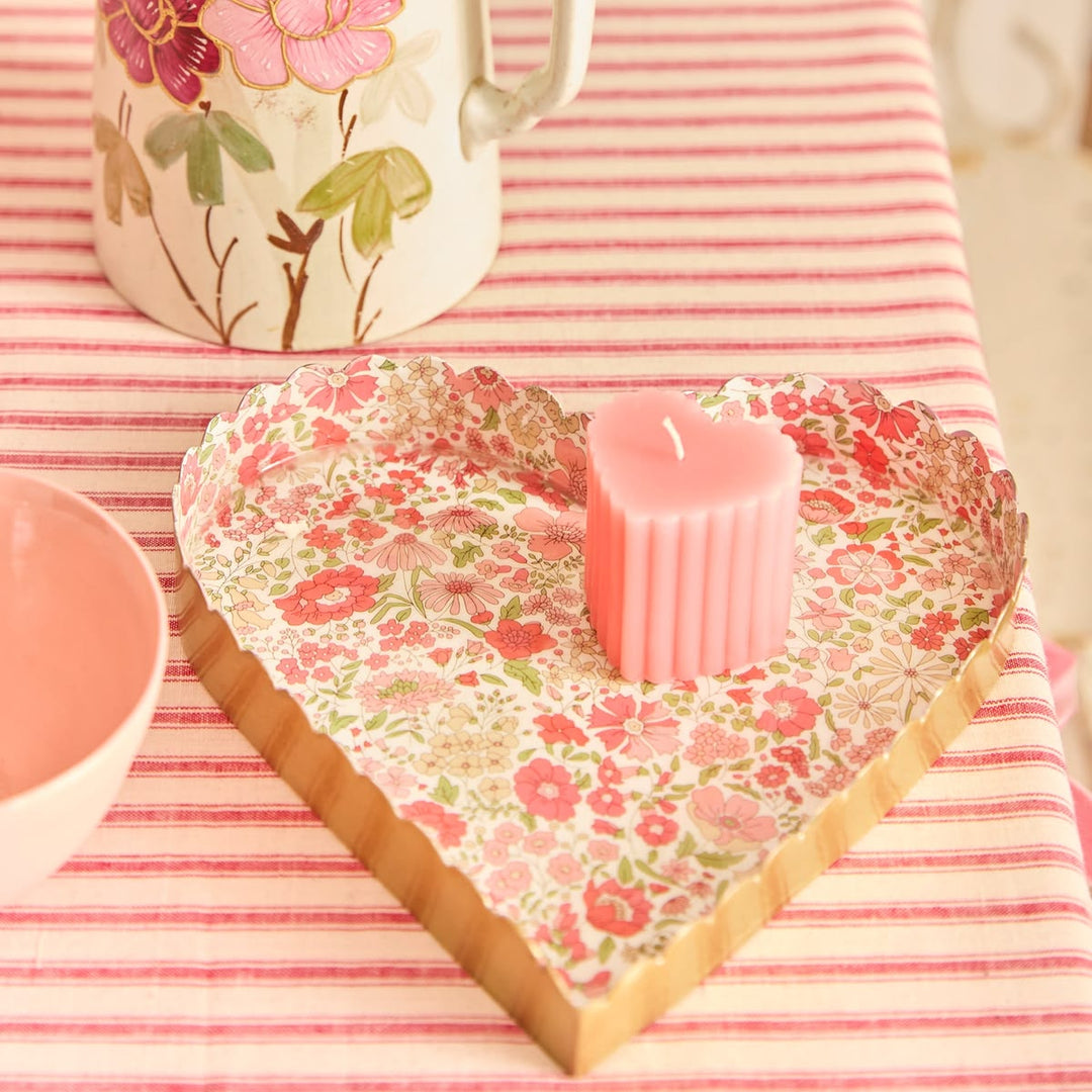 Heart-shaped floral coaster with a pink candle on a striped tablecloth