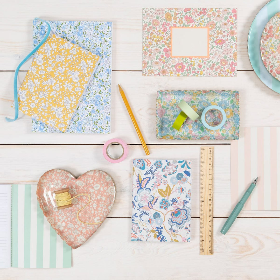 Assorted stationery items with floral patterns on a wooden surface