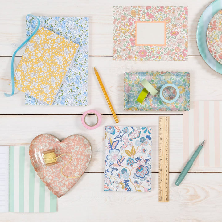 Assorted stationery items with floral patterns on a wooden surface