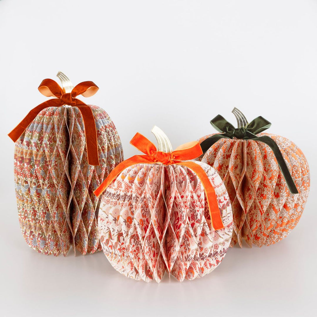 Three decorative pumpkins with ribbons on a white background