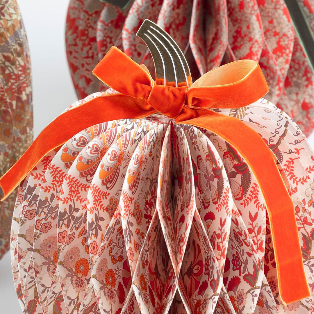 Decorative pumpkin with floral pattern and orange bow on a white background