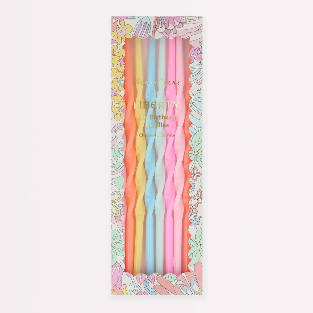 A boxed set of six twisted taper candles in pastel colors, displayed in a floral-patterned package. The visible candle colors are yellow, light blue, and pink, with gold 'Liberty' branding on the front.