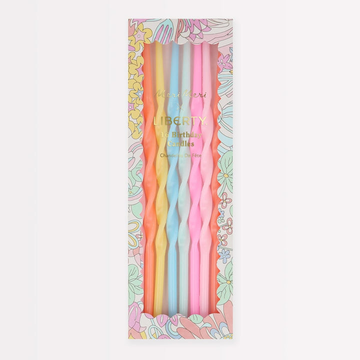 A boxed set of six twisted taper candles in pastel colors, displayed in a floral-patterned package. The visible candle colors are yellow, light blue, and pink, with gold 'Liberty' branding on the front.
