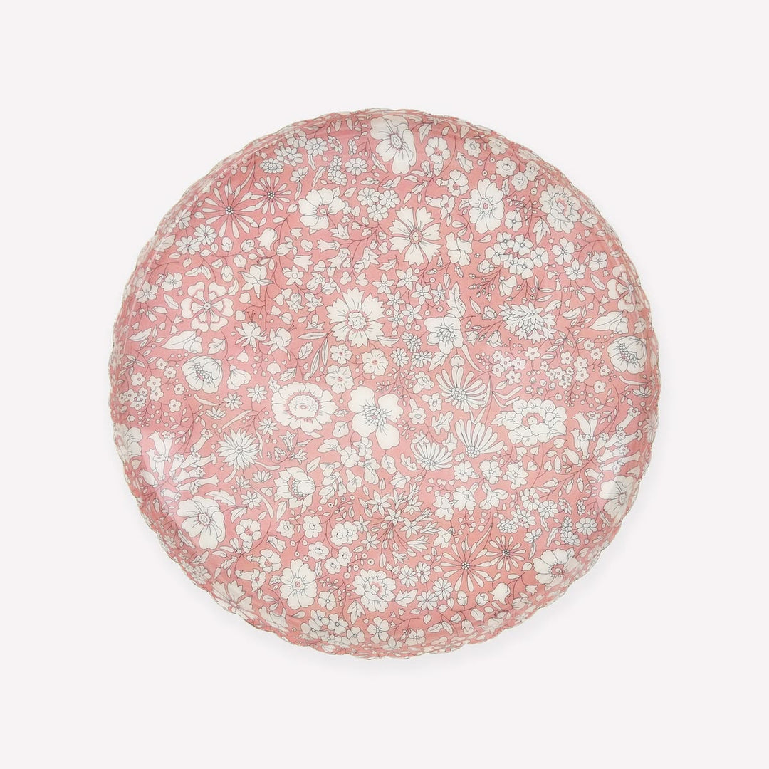 A round decorative tray or plate featuring a dense white and light gray floral pattern on a dusty pink background, shown from a top-down view against a light off-white backdrop.