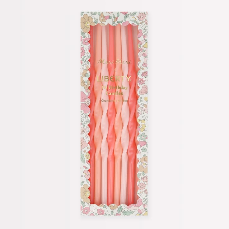 A boxed set of six twisted taper candles in soft pink and peach tones, displayed in a floral-patterned package on a light gray background.