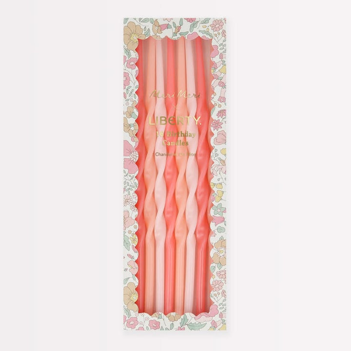 A boxed set of six twisted taper candles in soft pink and peach tones, displayed in a floral-patterned package on a light gray background.