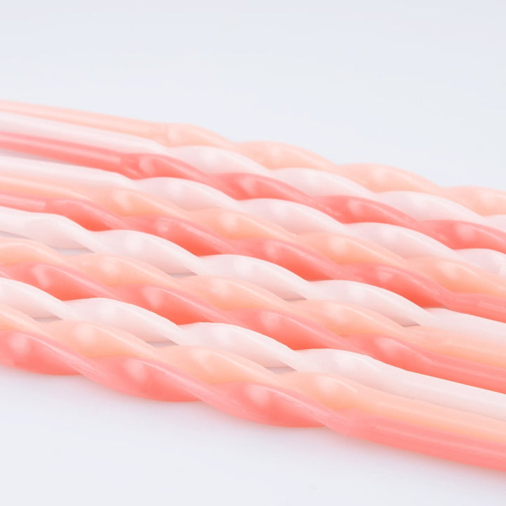 Twisted rope-style cords in a soft coral pink and pale peach color, shown in a close-up studio shot on a white background.