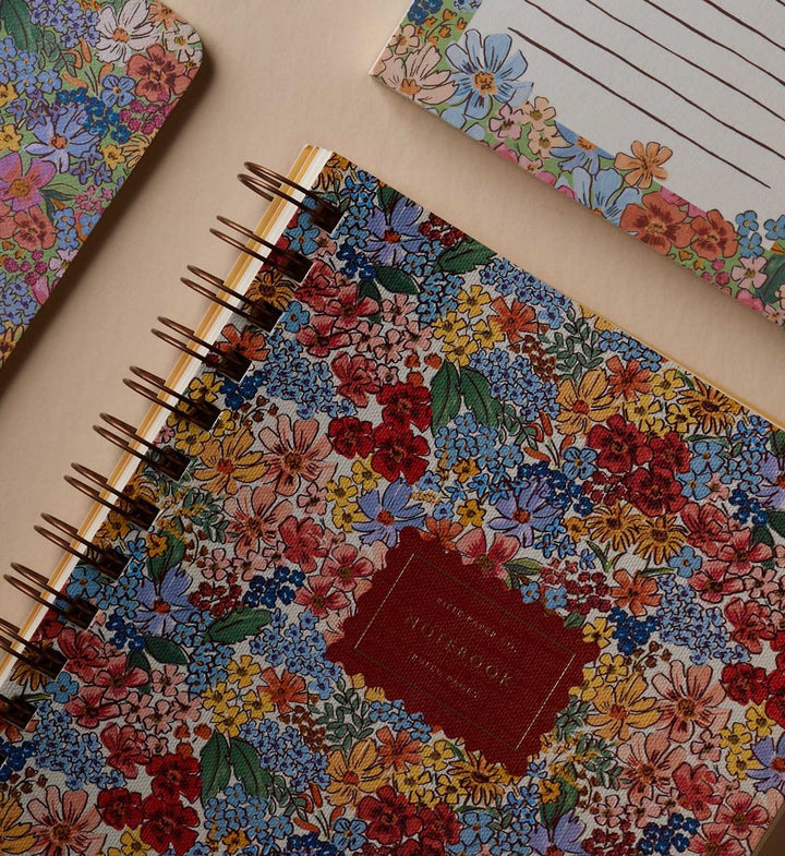 Floral-patterned notebook with a red label on a beige surface