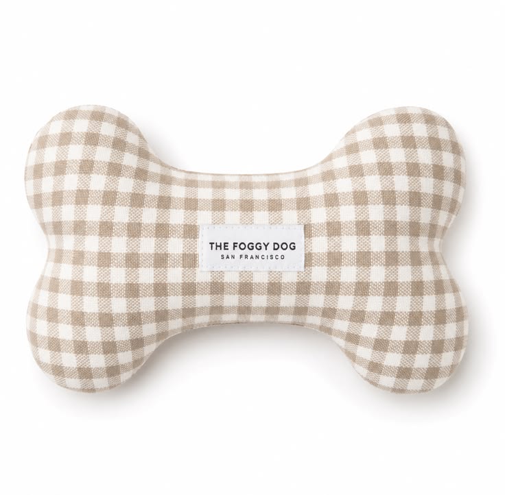 A bone-shaped dog toy made of beige and white gingham fabric, featuring a white label in the center that reads 'THE FOGGY DOG SAN FRANCISCO'.