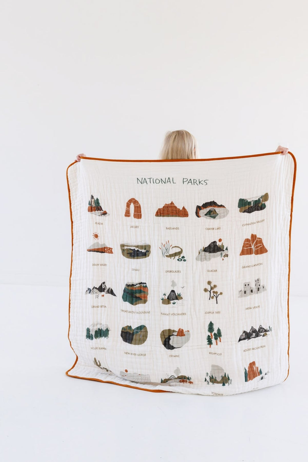 Person holding a blanket with national park illustrations on a white background