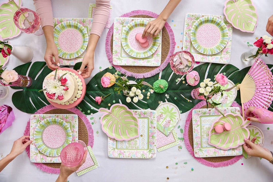 Table setting with pink and green plates, napkins, and floral decorations.