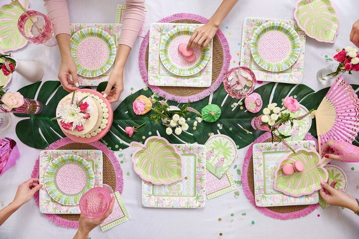 Table setting with pink and green plates, napkins, and floral decorations.