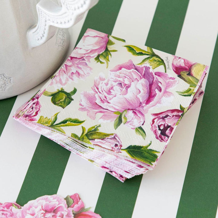 Floral-patterned napkins on a green and white striped surface with a teapot.