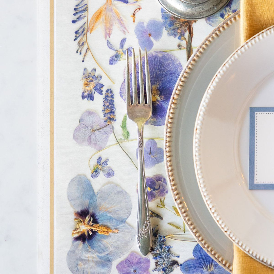 Floral placemat with silverware on a white surface