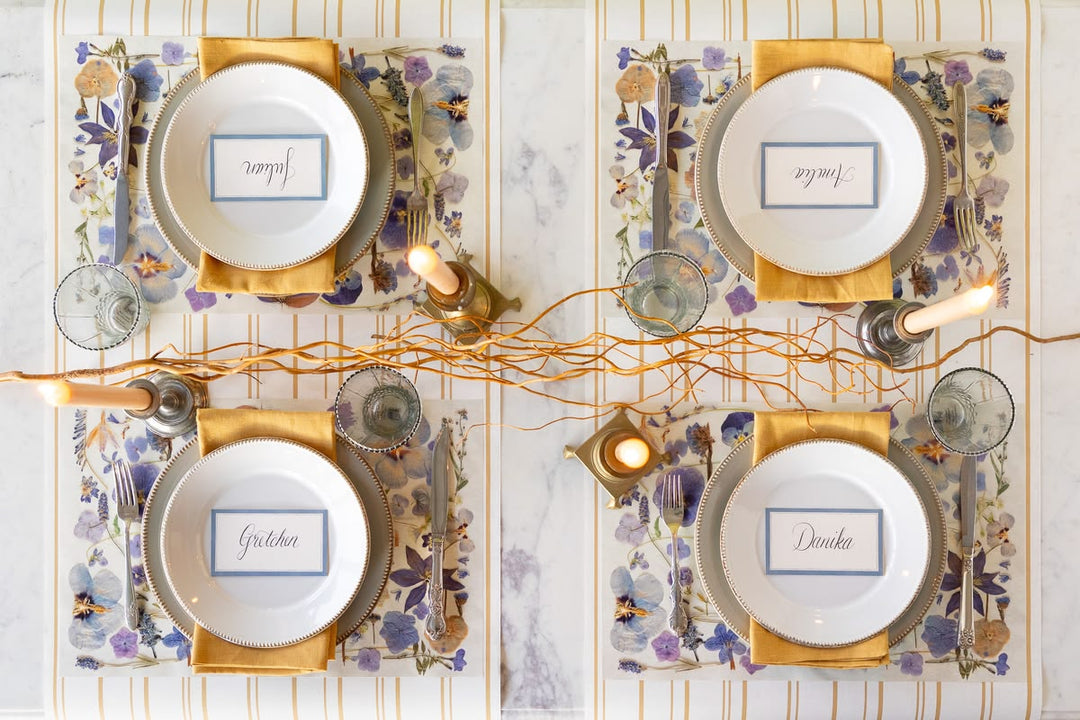 Decorative table setting with place cards and candles on a marble surface
