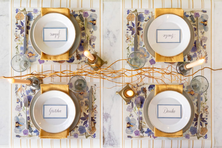 Decorative table setting with place cards and candles on a marble surface
