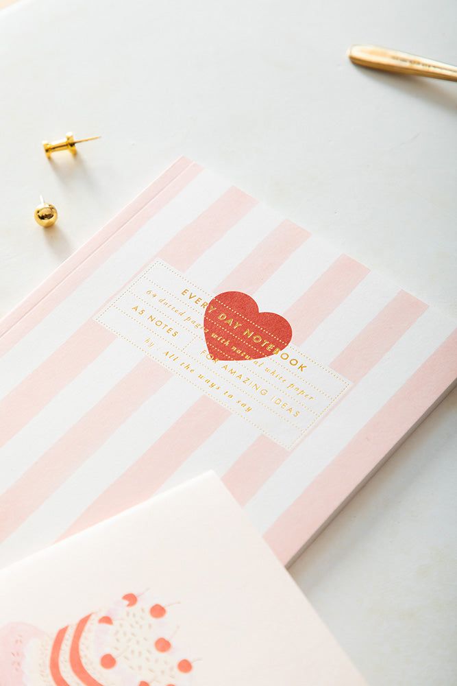 Pink and white striped box with a heart-shaped label on a light background