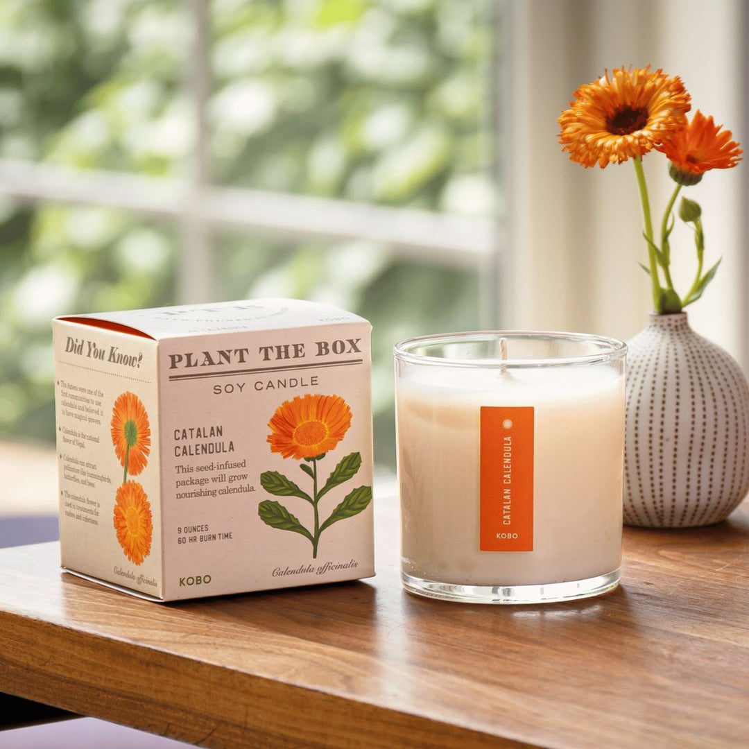 Candle and packaging with floral design on a wooden surface