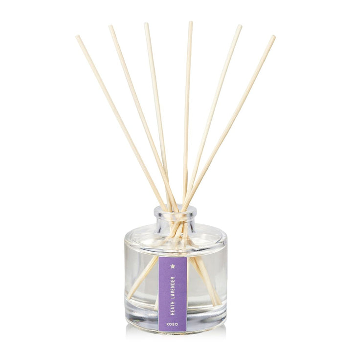Clear glass diffuser bottle with wooden sticks and a purple label on a white background