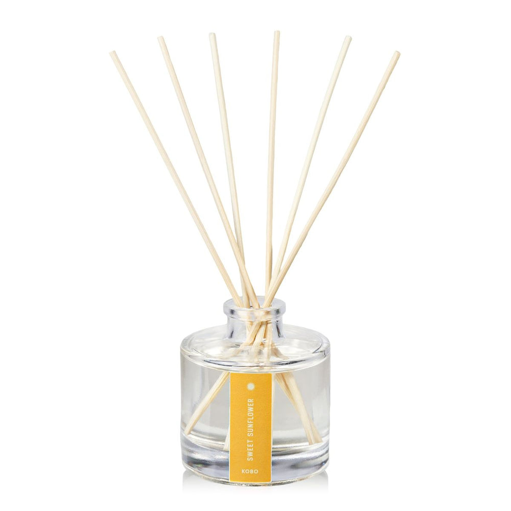 Clear glass diffuser bottle with wooden sticks and a yellow label on a white background