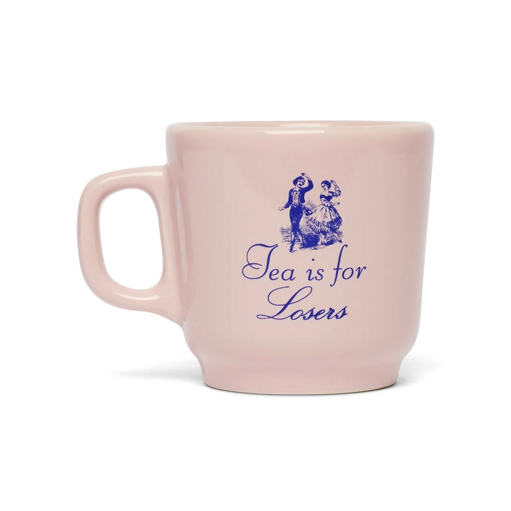 A light pink ceramic mug with a blue illustration of a bear and a girl and the text 'Tea is for Losers' printed on the front, set against a plain white background.