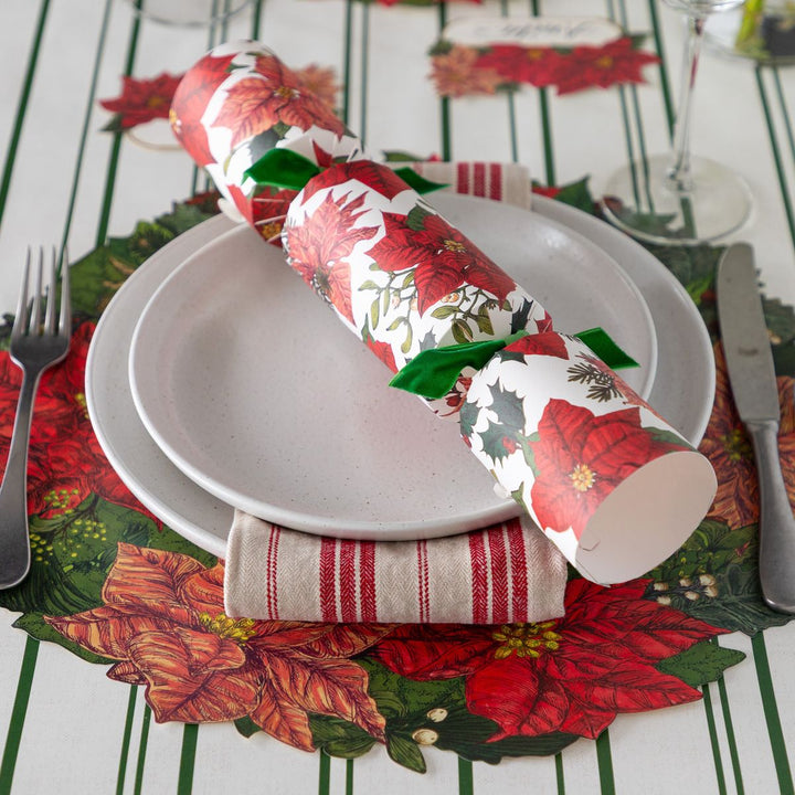 Christmas-themed table setting with crackers, plates, and cutlery on a decorative tablecloth.