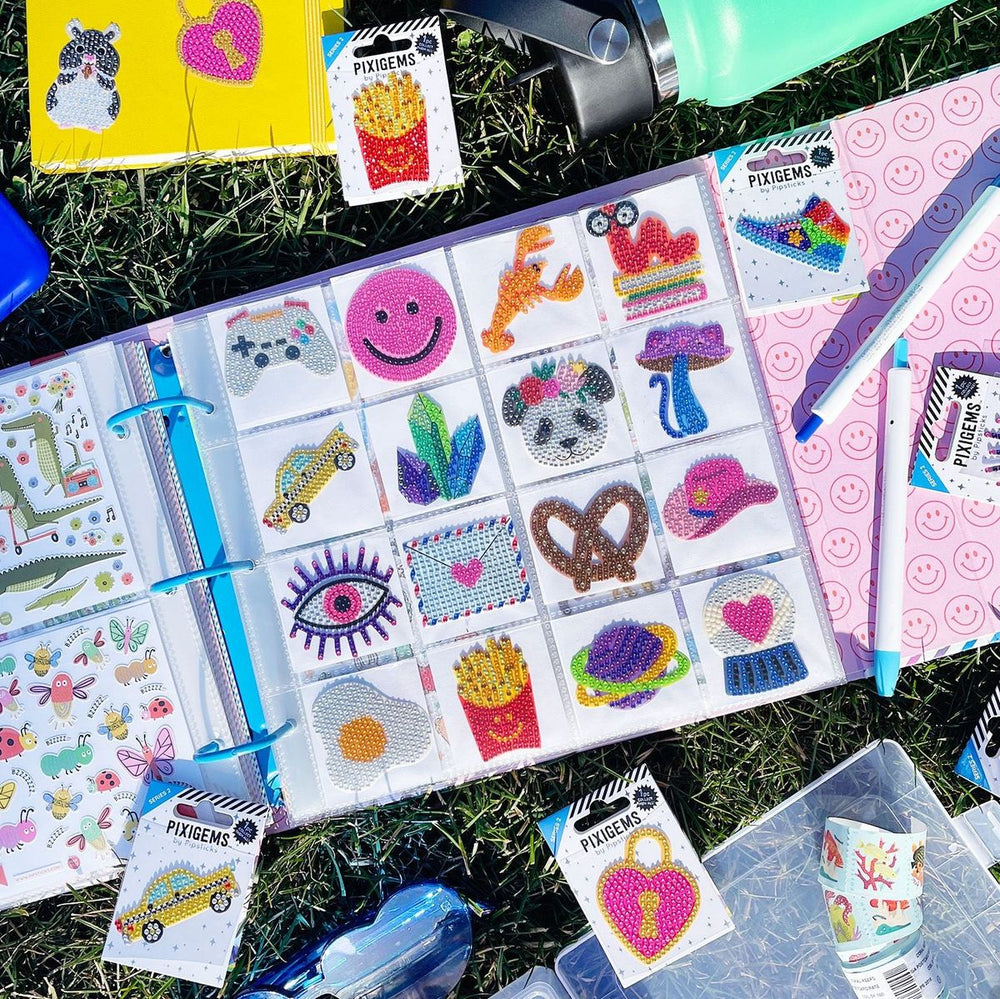 Pixie Gems decorative stickers on a binder with additional stickers scattered on grass