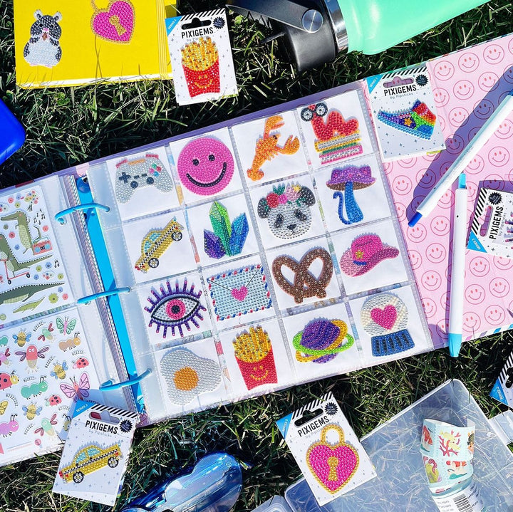 Pixie Gems decorative stickers on a binder with additional stickers scattered on grass