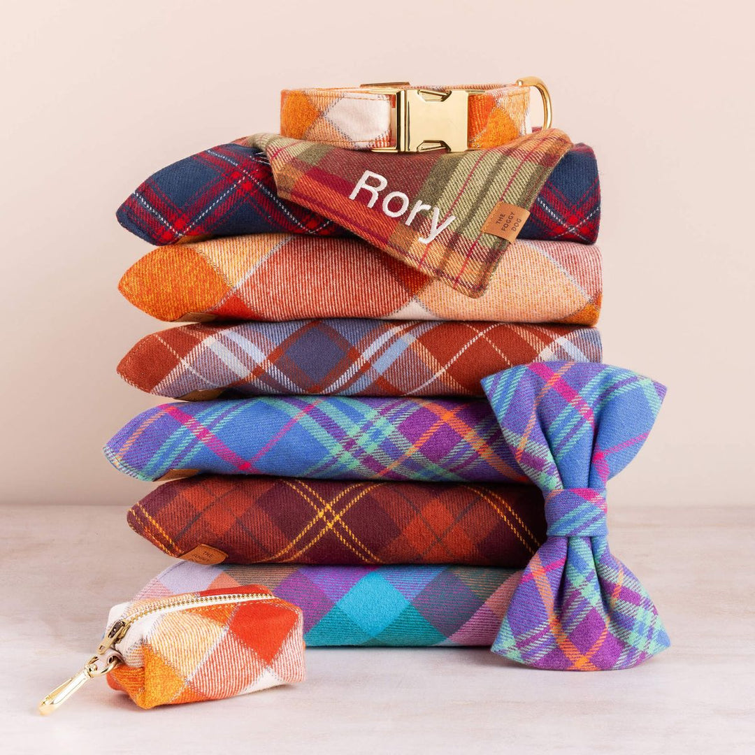 Stack of colorful plaid pouches with a gold buckle and 'Rory' branding on a beige background.