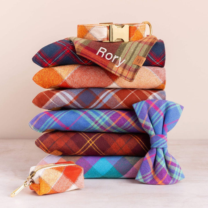 Stack of colorful plaid pouches with a gold buckle and 'Rory' branding on a beige background.