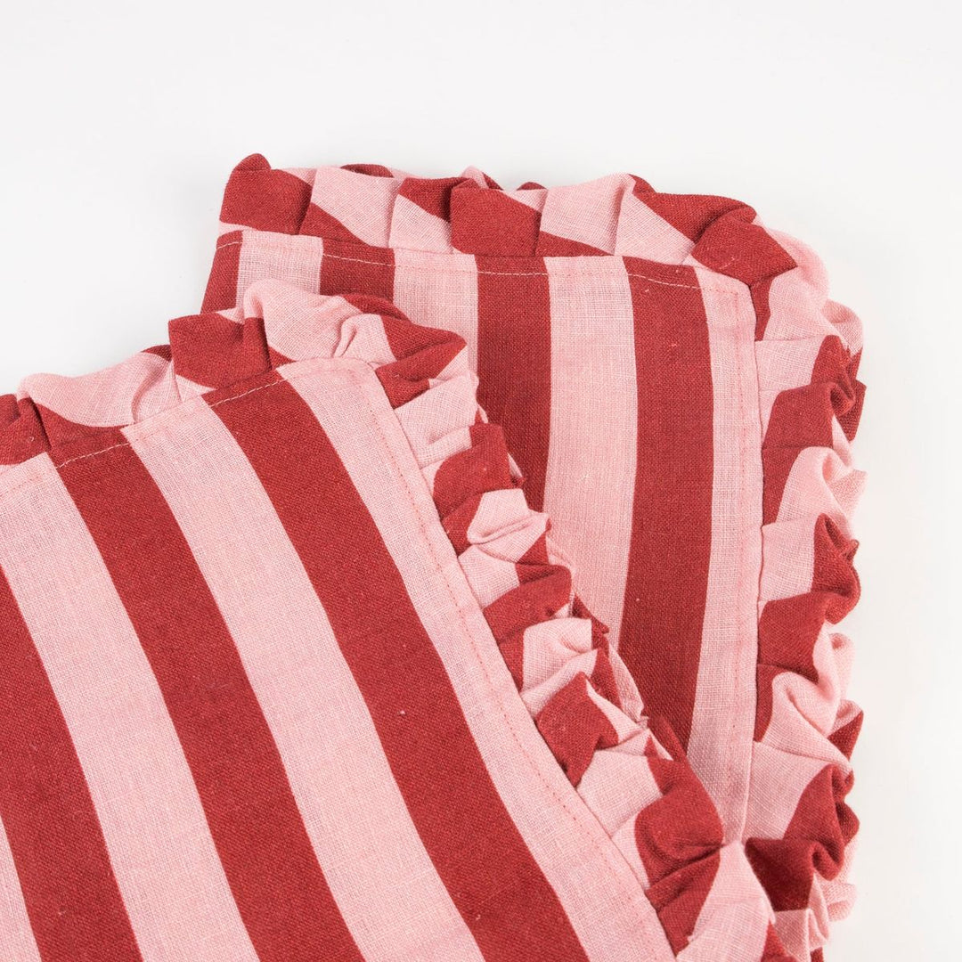 Close-up of red and pink striped fabric with ruffled edges on a white background