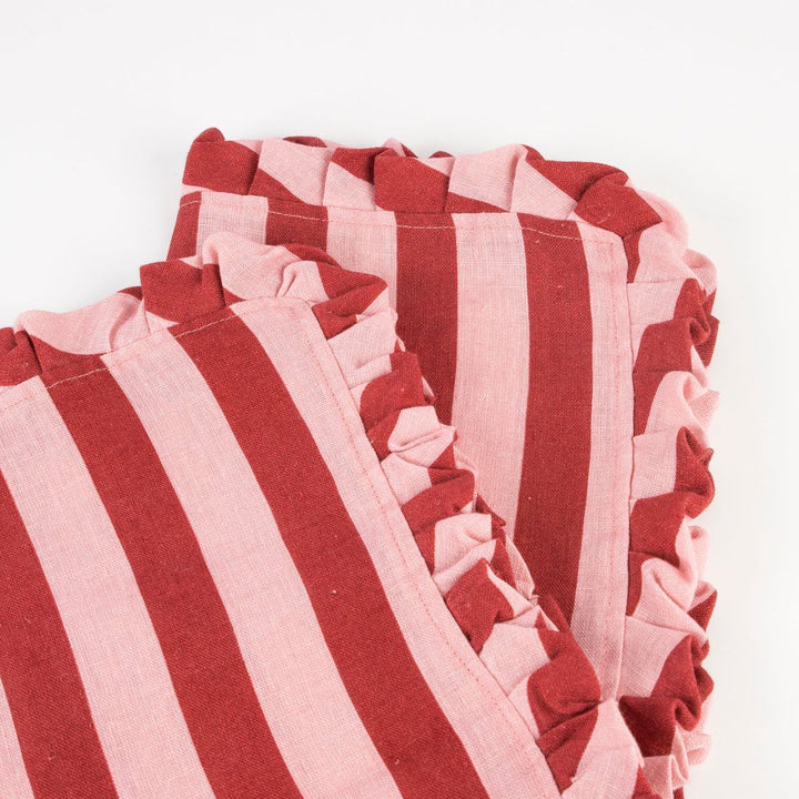 Close-up of red and pink striped fabric with ruffled edges on a white background