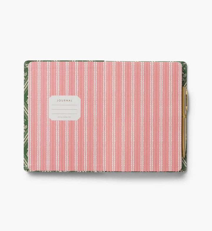 A hardcover journal with a pink and white vertical stripe pattern on the cover, featuring a white label that reads 'JOURNAL' and a gold pen tucked into the side pocket, set against a plain white background.