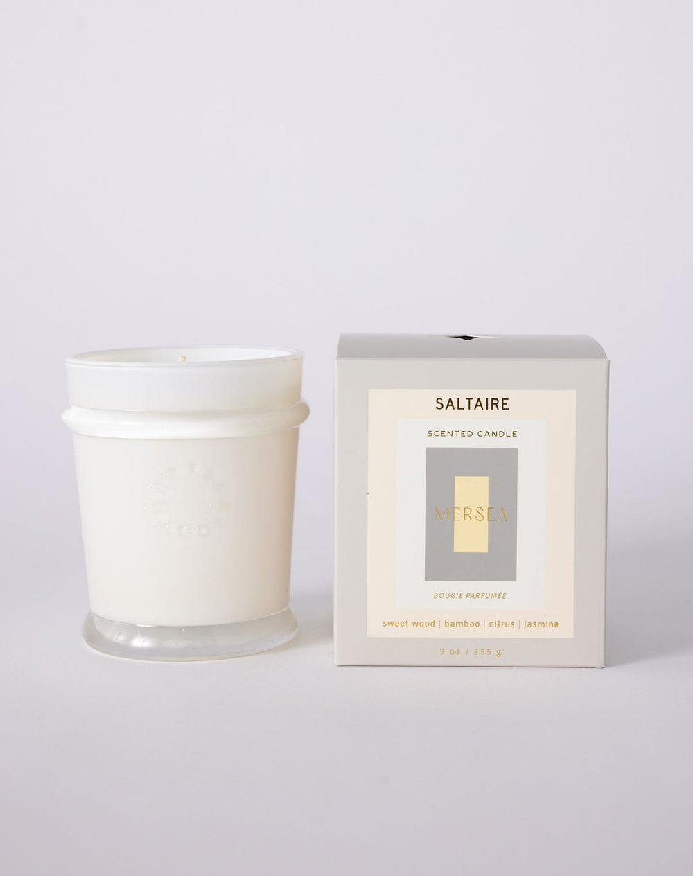 White candle with 'Saltaire' packaging on a light gray background